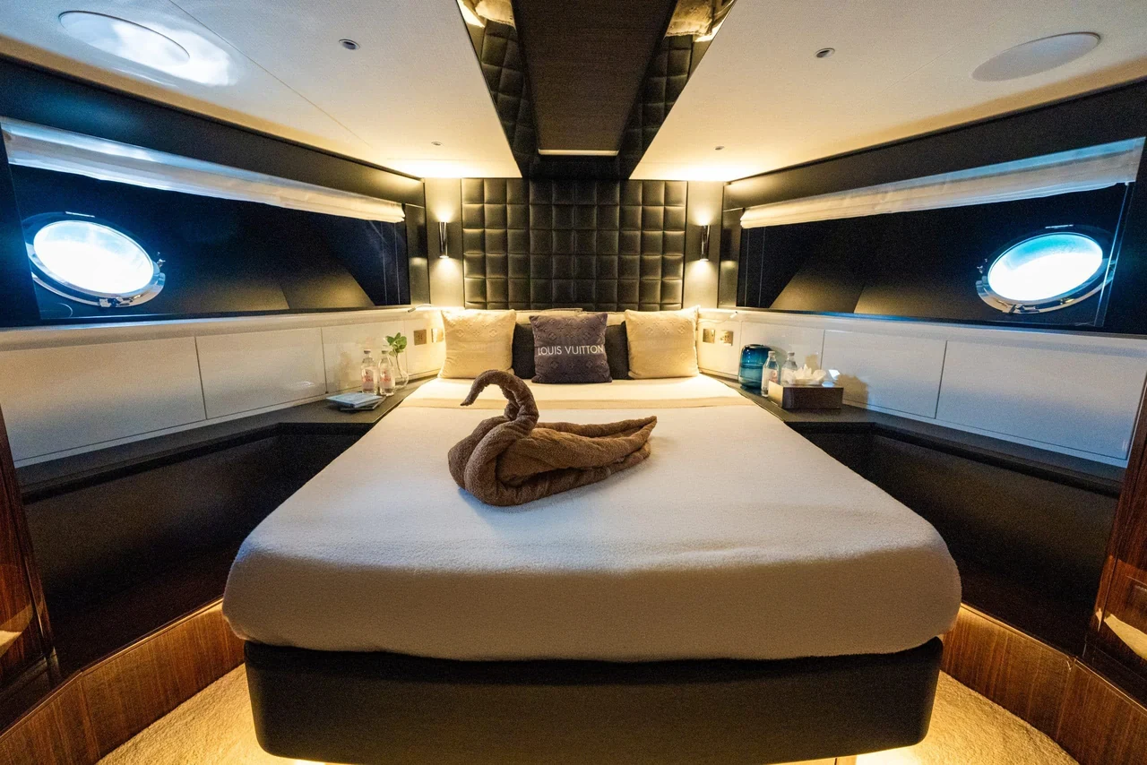 Double cabin aboard Riva 82 with oval portholes and padded headboard