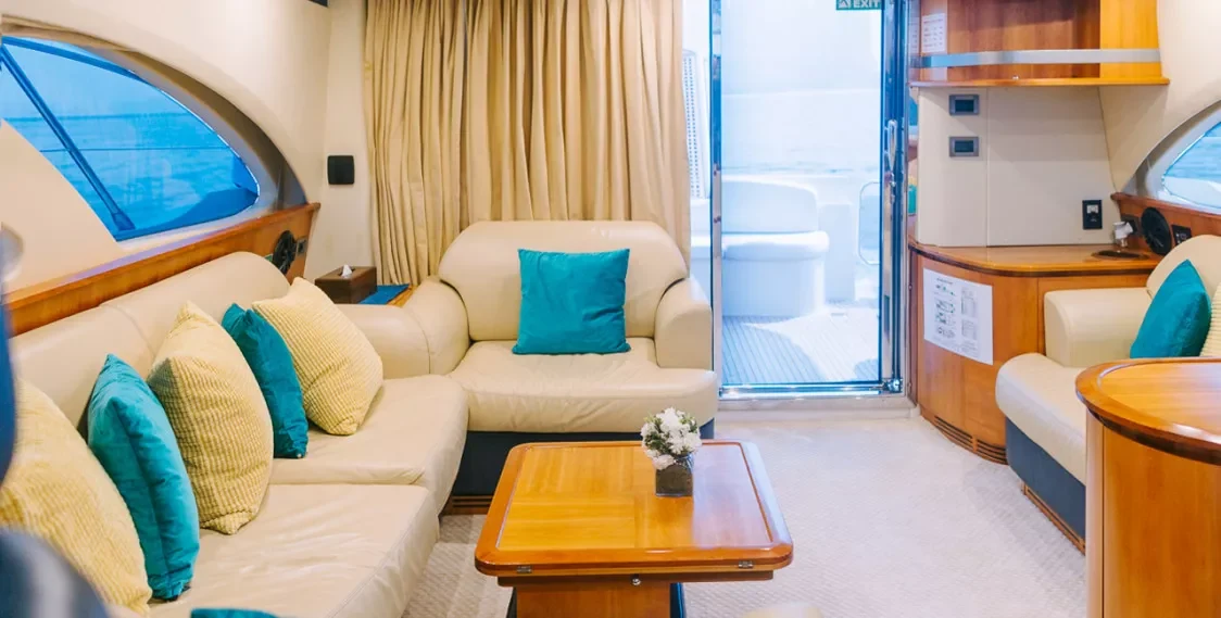 Pale salon seating and warm wood cabinetry aboard Elite Monica