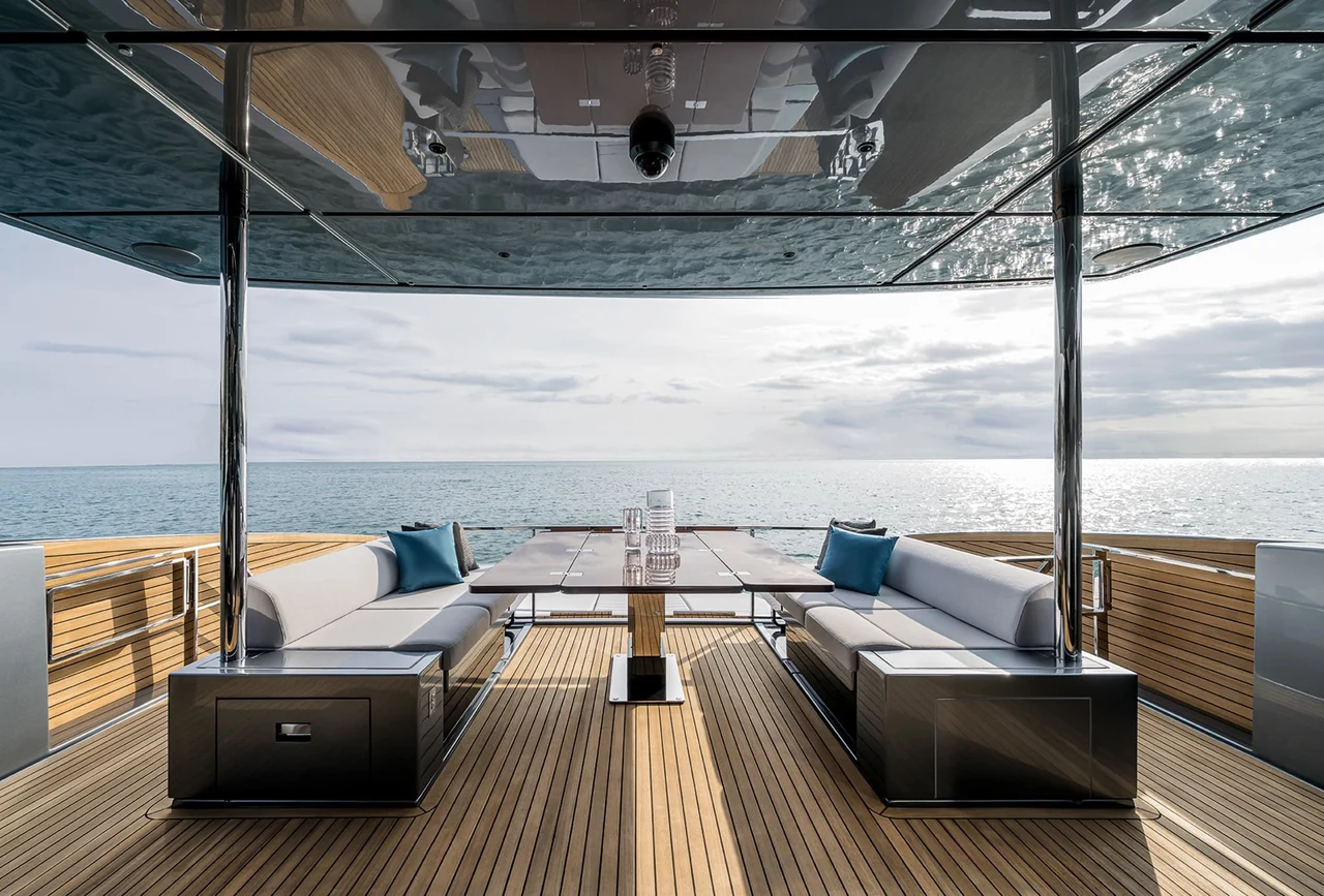 Sheltered outdoor dining table and facing sofas aboard Riva 82